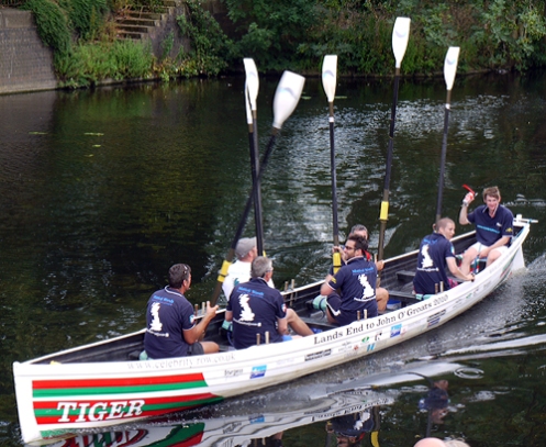 Tiger and crew raise their oars in salute as they arrive